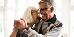 Un couple âgé souriant, dansant main dans la main pour célébrer leurs noces de diamant, symbolisant 60 ans de mariage et de bonheur partagé.