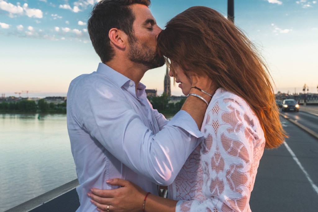 Couple s’enlaçant tendrement sur un pont au coucher du soleil pour célébrer leurs 3 ans de mariage l 3rd wedding anniversary - Bracelets Kern